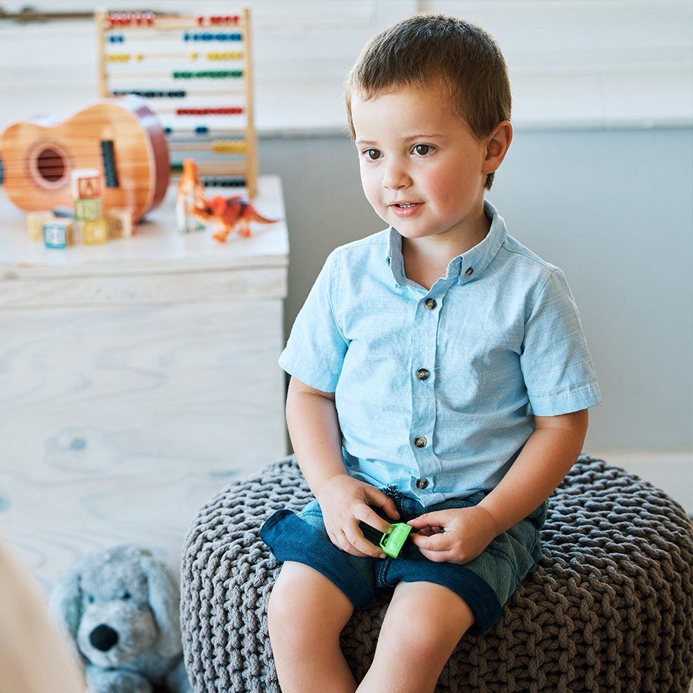 Little boy sitting on a stool and talking with an adult inside home